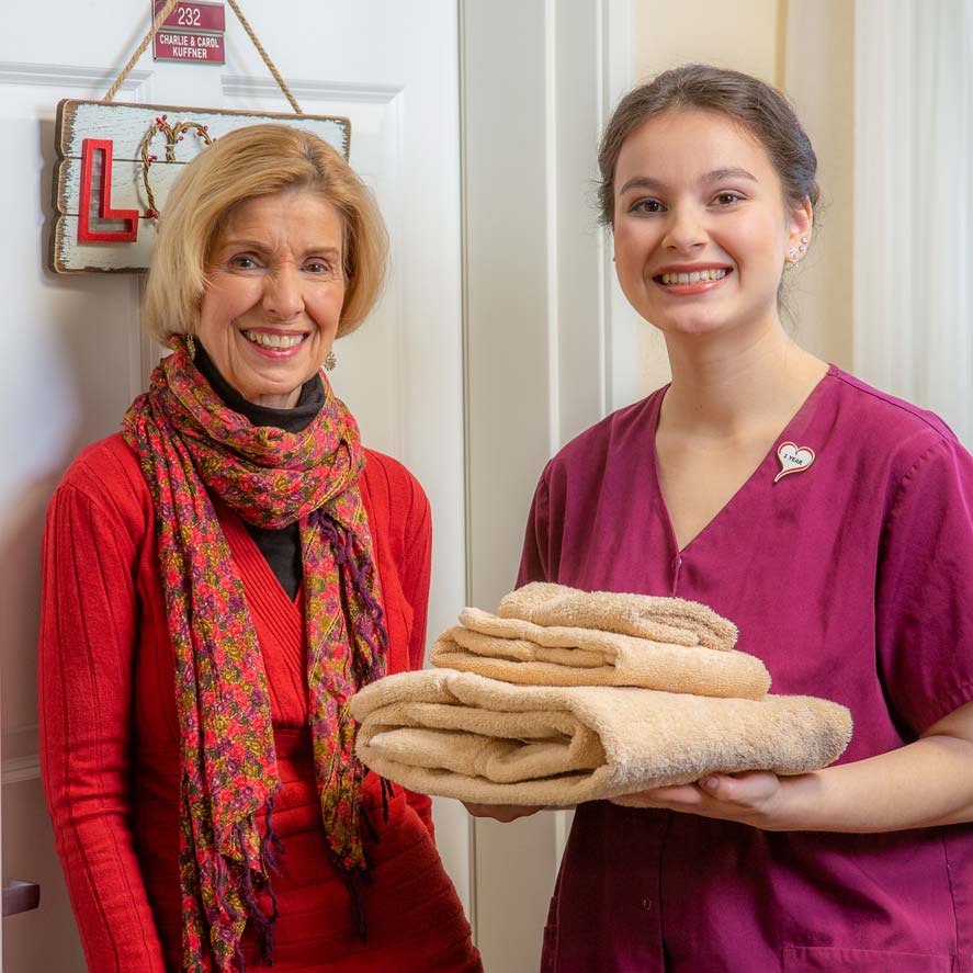 A team member delivering fresh linens to a resident at Sterling Heights